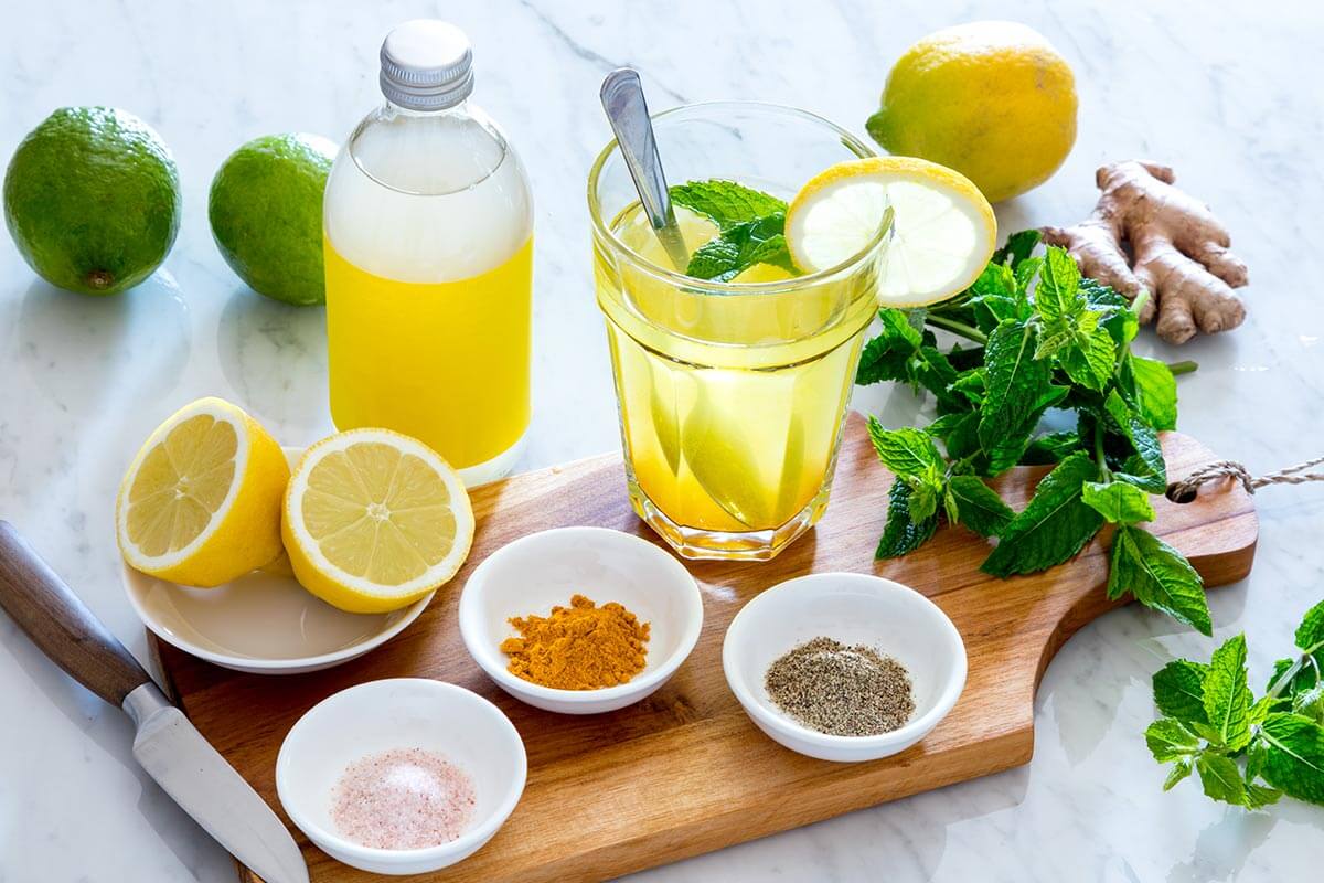 glass of lemon water with other healthy foods on a wooden board