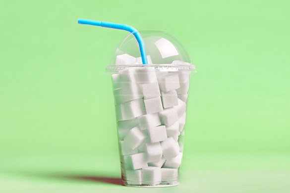 plastic cup filled with sugar cubedgreen background